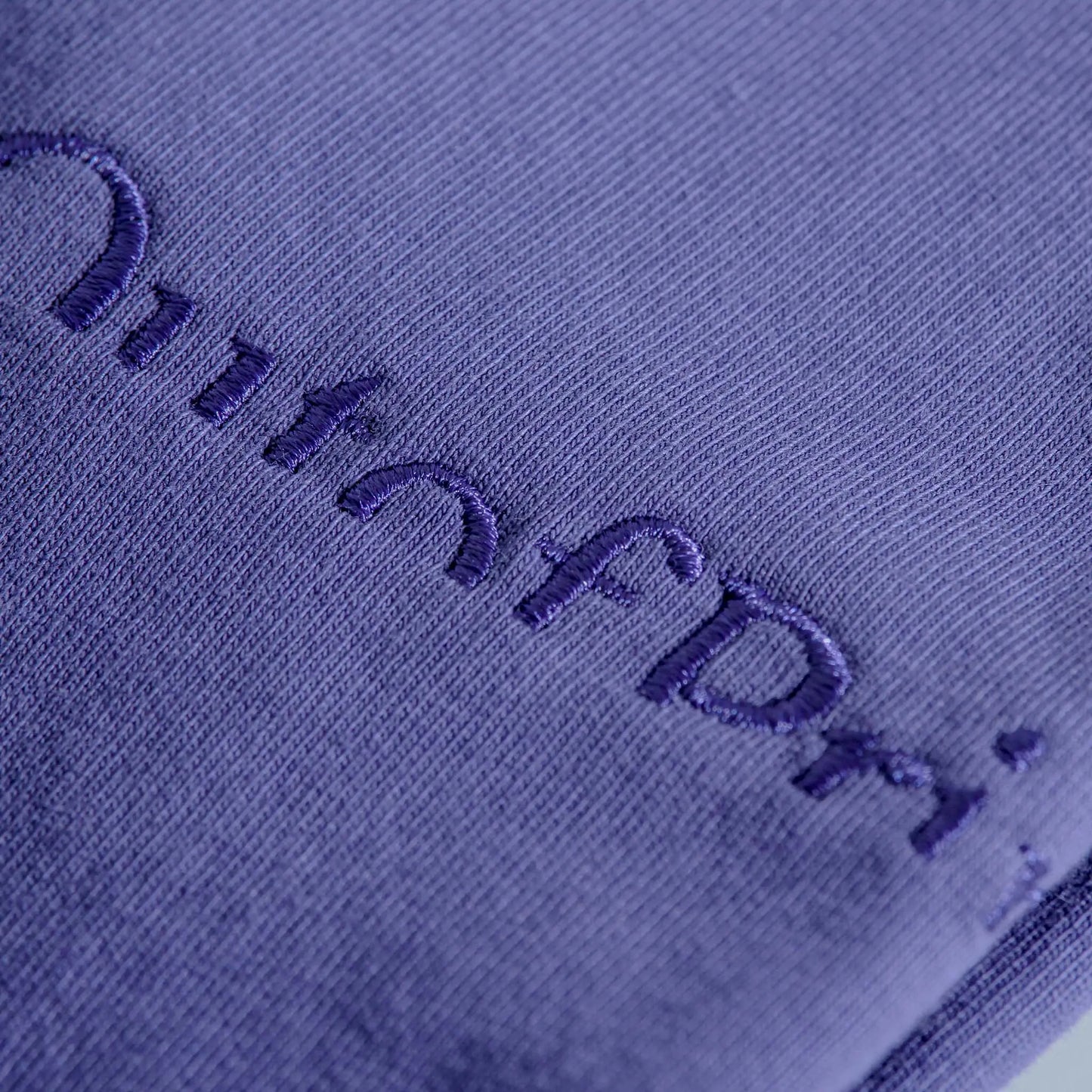 Close-up of a textured purple fabric with embroidered text.