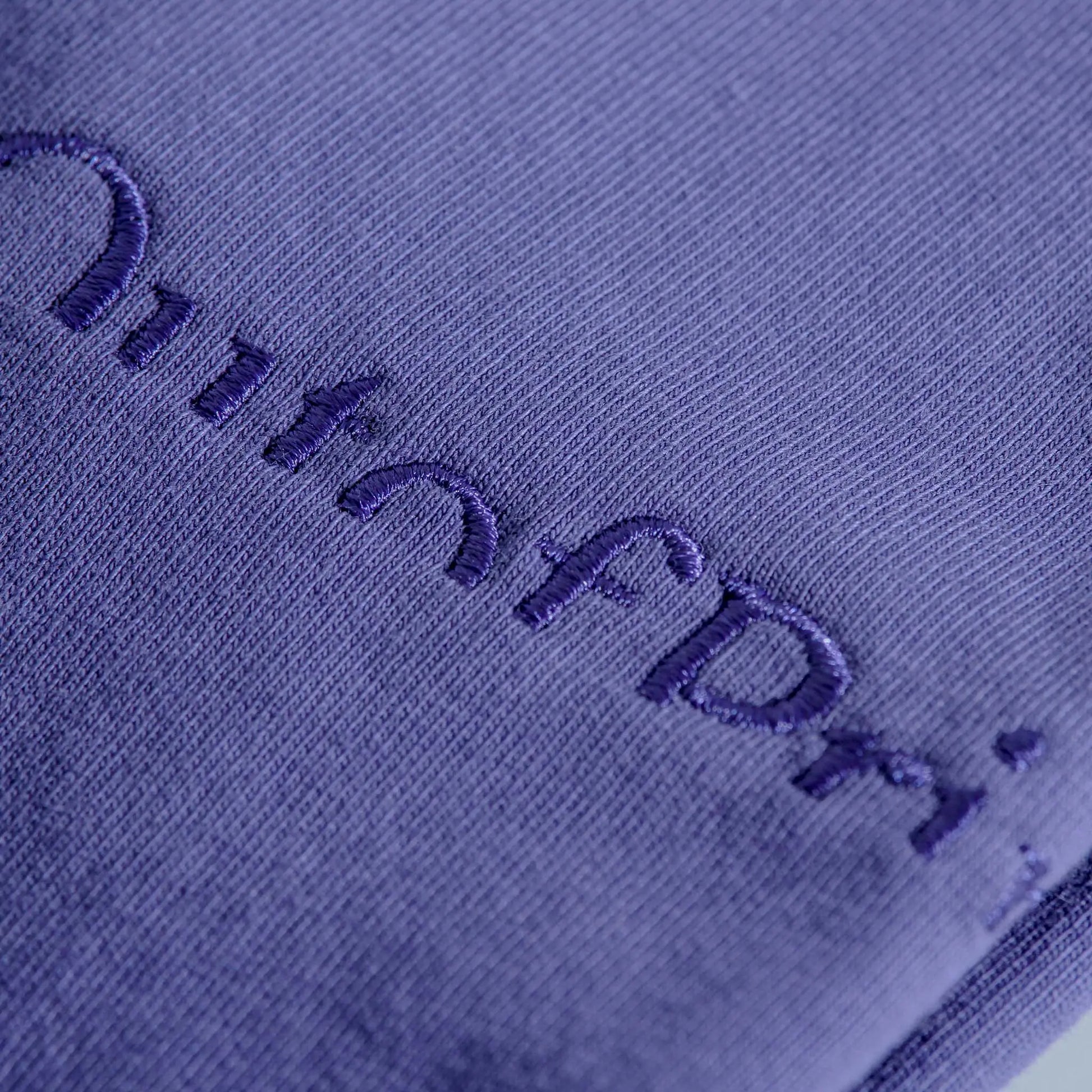 Close-up of a textured purple fabric with embroidered text.