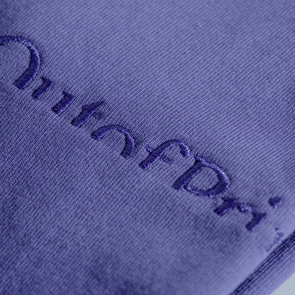 Close-up of a textured purple fabric with embroidered text.